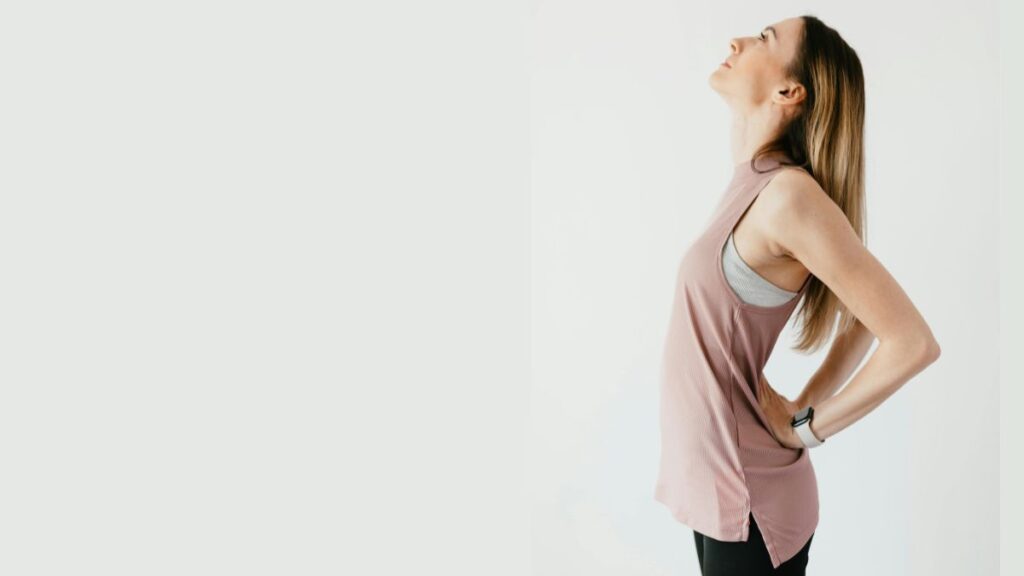 Rückenschmerzen was tun – Frau mit Hand im unteren Rücken